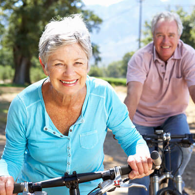 Mature Woman and Man Riding a Bike While Smiling